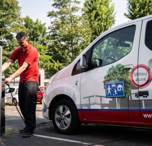 Foto van man die bestelbus elektrisch oplaadt